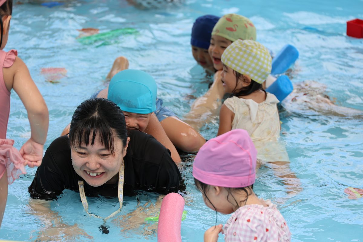 家庭的な雰囲気の室内で園児と保育士が一緒に食事をする写真